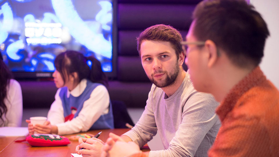 Three students sitting and talking together at a table on the Loughborough University campus